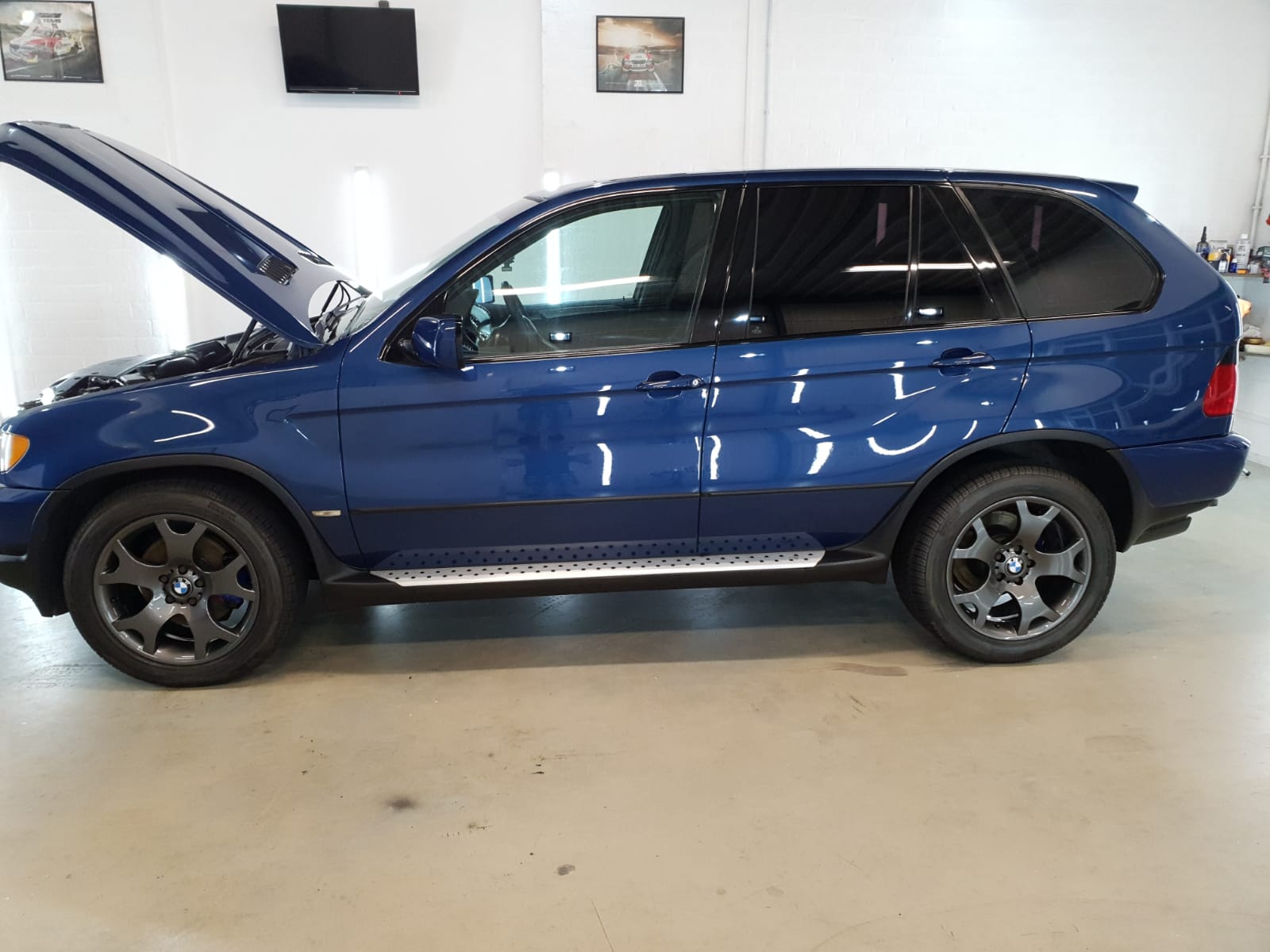 Een blauwe BMW X5 met open motorkap in de werkplaats