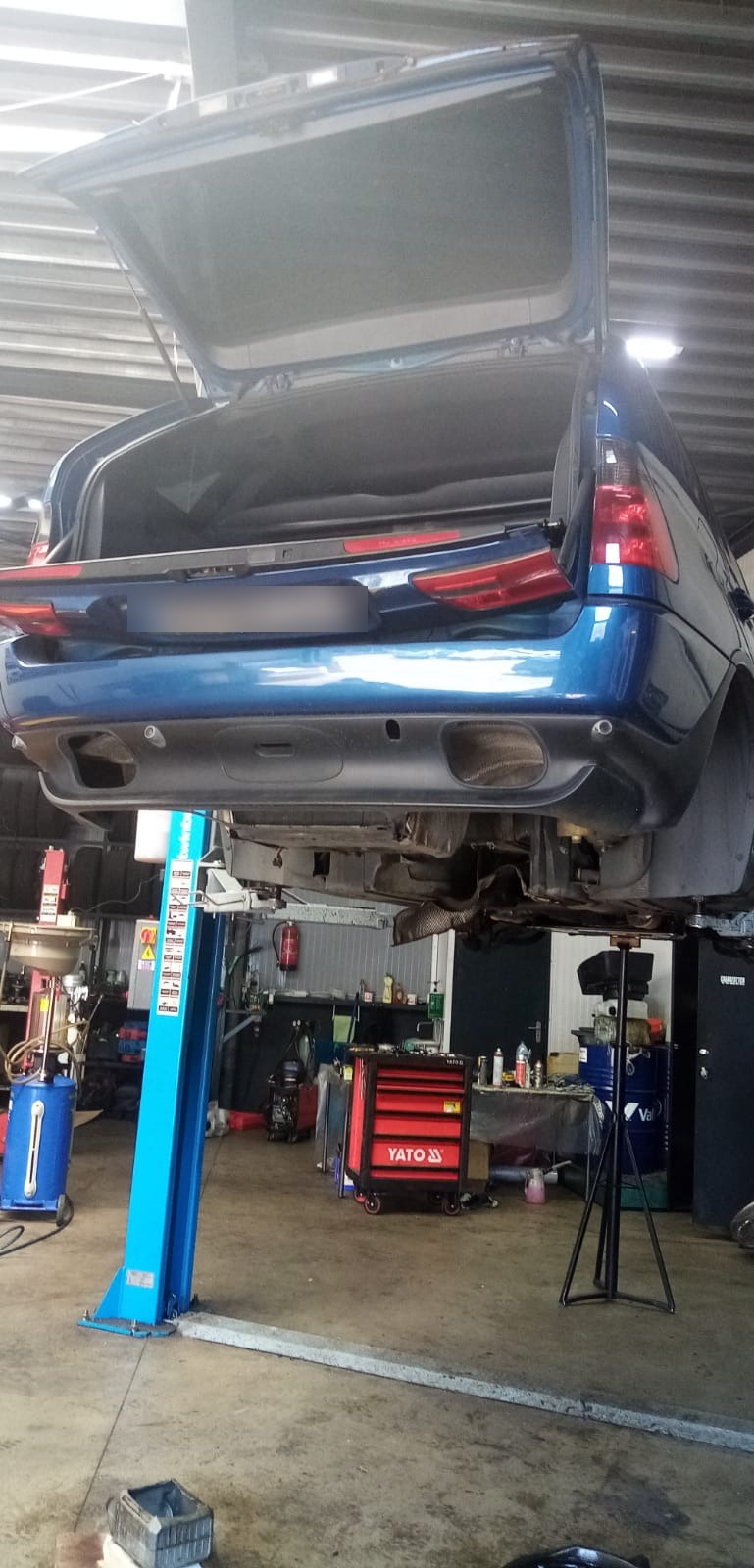 Een auto op een hefbrug in de werkplaats, met de kofferklep open