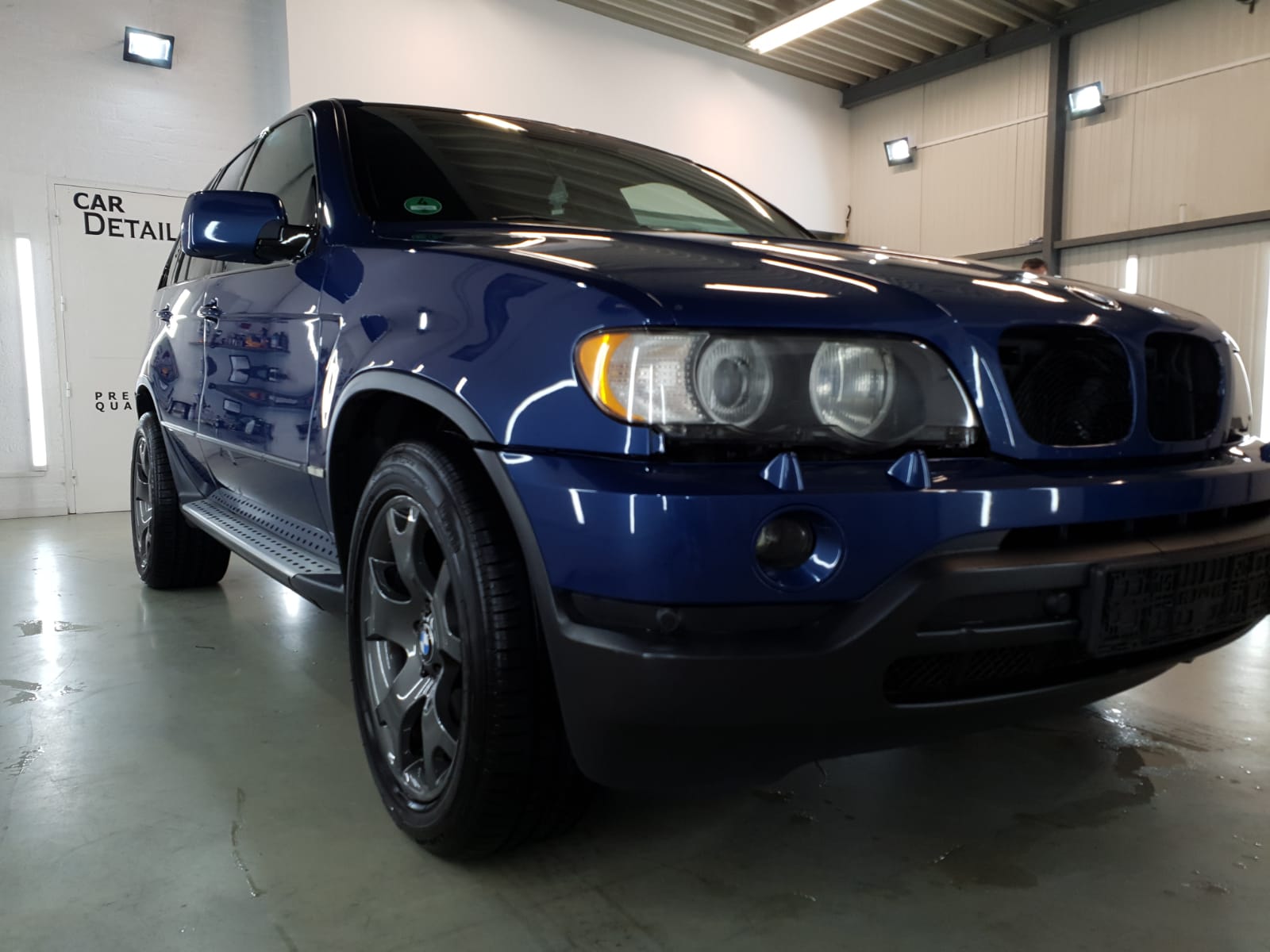 De voorkant van een blauwe BMW X5 in de werkplaats